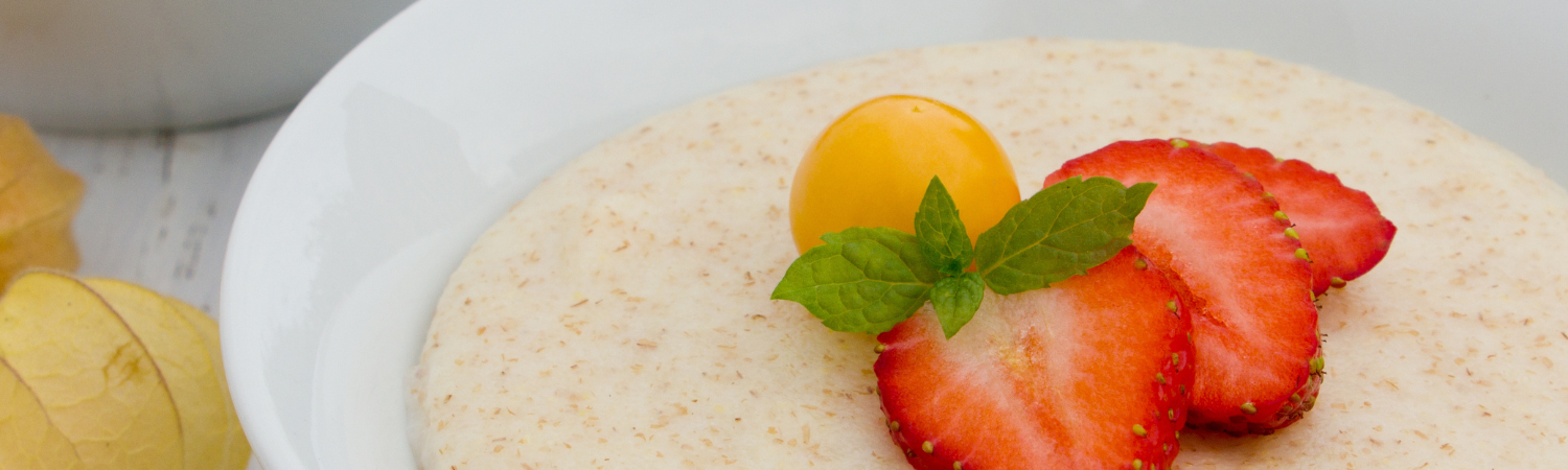 Weiße Schale gefüllt mit Grieß und angerichtet mit Erdbeeren, Physalis und Minze