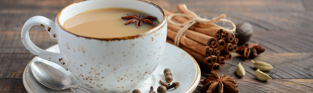 Eine Tasse Tee und daneben liegen Zimtstangen und Anissterne