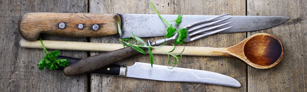 Ein großes Messer, eine Gabel, ein weiteres Messer und ein Holzlöffel
