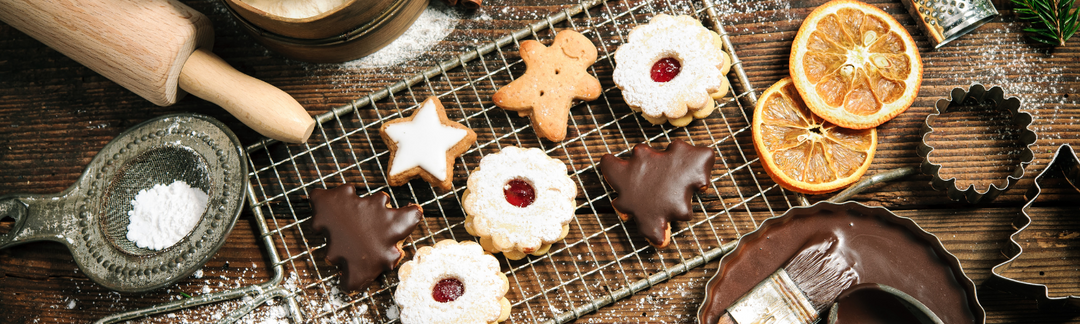 Weihnachts-Plätzchen liegen neben Backzutaten auf einem Gitter